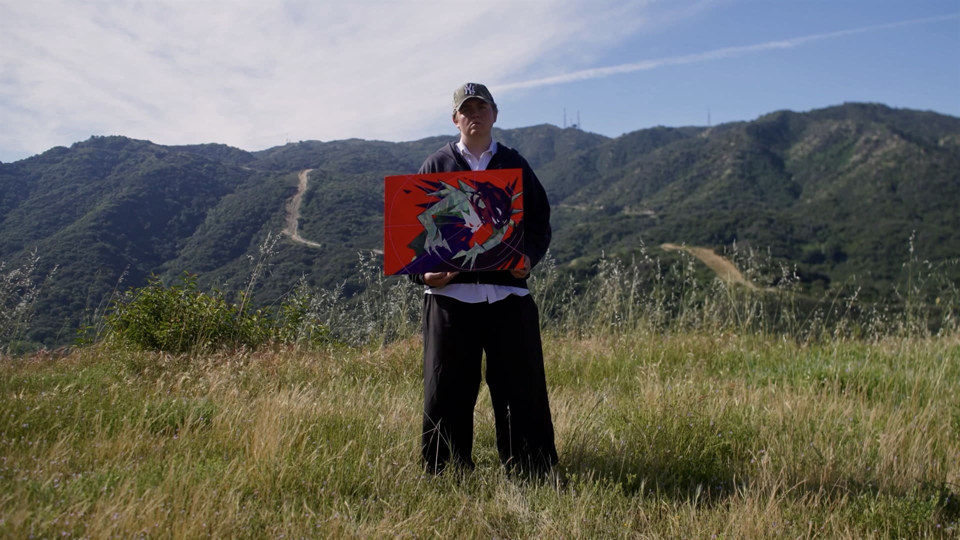 Lucas Chatham holding a painted panel outdoors